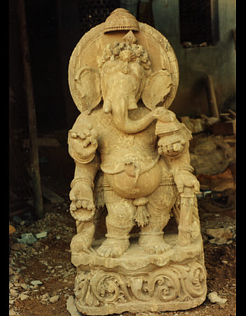 Divine Ganesha sculpture with ornate headpiece and blessing gesture in handcrafted sandstone