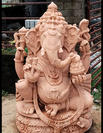 Handcrafted Lord Ganesh idol with serene expression and traditional jewelry in natural sandstone